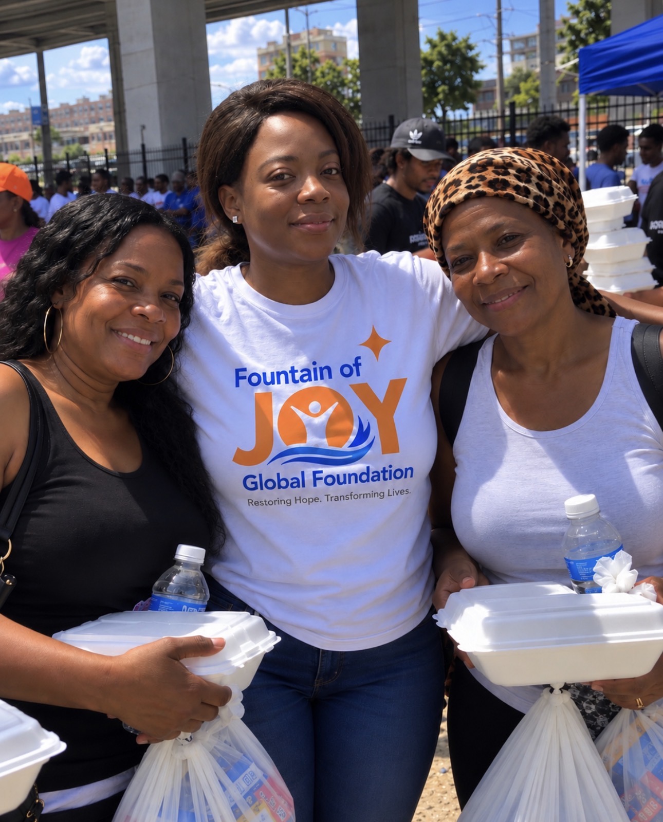 Three smiling women sharing meals at a community outreach gathering